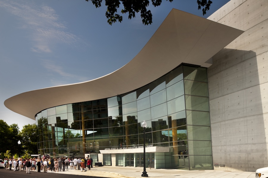 A crowd gathers outside the Arena Stage at the Mead Center under its dramatic curved roof.