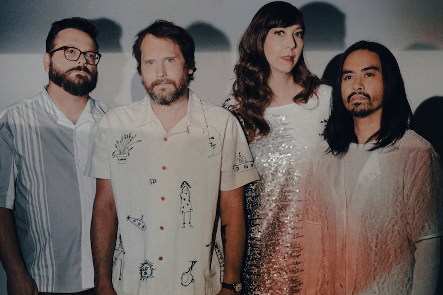 The band Silversun Pickups poses together in soft lighting against a gray backdrop.